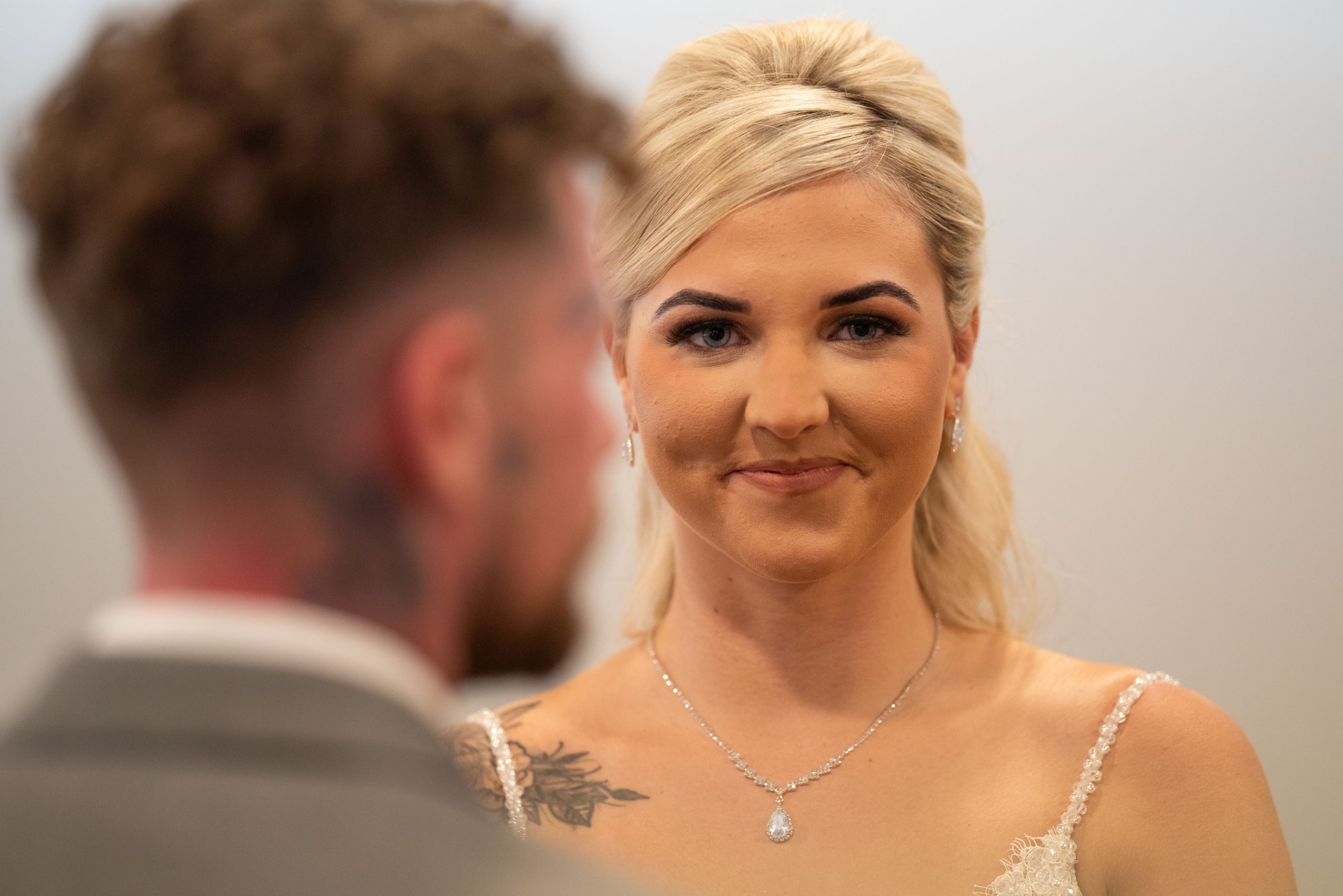 Bride in white dress smiling at groom during wedding ceremony